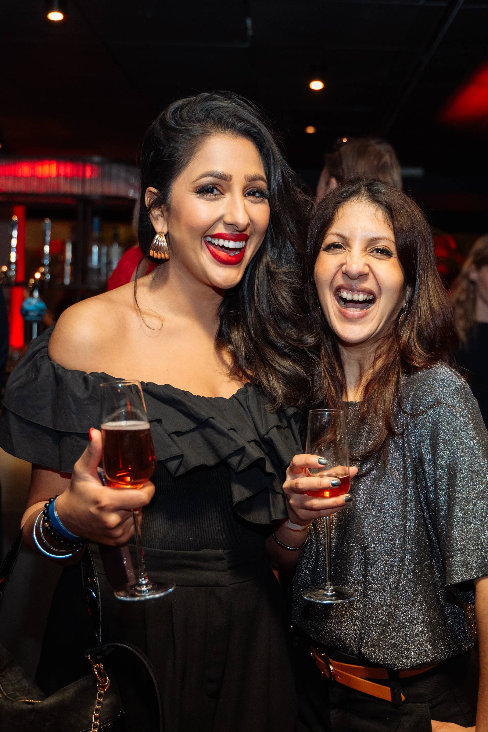 Two attendees laughing, with glasses of wine